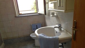 Une salle de bain avec un lavabo, des toilettes et une fenêtre.