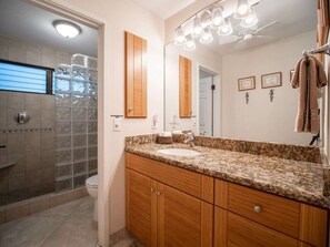 Enjoy a refreshing shower in the bathroom with a granite sink, wooden cabinetry, and a large mirror.