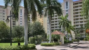 A courtyard with palm trees, a small gazebo, and a building with multiple balconies. - Directly across Ritz Carlton Naples Beach Resort!!! (Naples)
