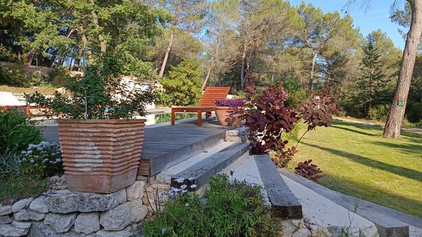 A stone pathway leading to a wooden bench with a potted plant beside it. - Nature in Aix (Venelles)