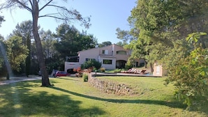 A two-story building with a stone wall and a grassy lawn. - Nature in Aix (Venelles)