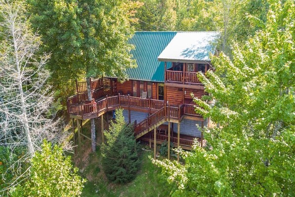 Una baita con veranda in legno e più livelli, immersa in una fitta foresta.