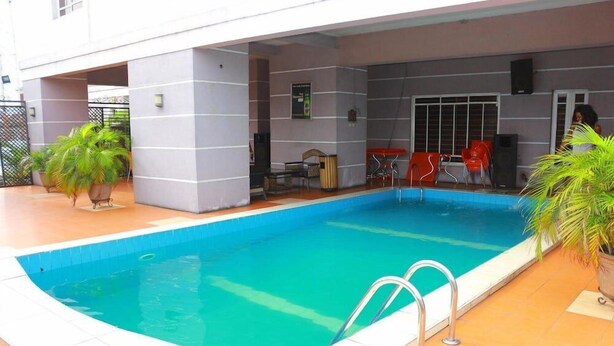 An indoor swimming pool with a tiled deck, surrounded by potted plants and outdoor seating. - Zaro Suites and Lounge Kano (Kano)