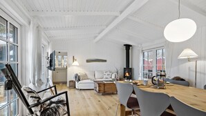 Una habitación acogedora y bien iluminada con una mesa de madera, sillas, un sofá y una chimenea.