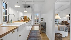 Una cocina moderna con armarios blancos, encimera de madera y un ventanal grande.