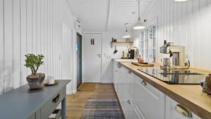 Una cocina estrecha con paredes de madera blanca, una encimera de madera y una estufa empotrada.
