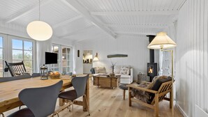 Amplia sala de estar con una mesa de comedor de madera, asientos cómodos, chimenea y ventanas grandes.