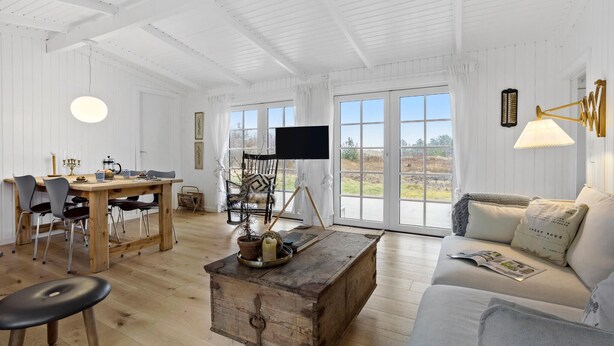 Un salón espacioso con una mesa de comedor de madera, un sofá y un televisor.