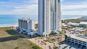 A high-rise hotel with multiple floors, a parking area, and a beach view. - Life is beautiful at Sapphire on SPI! (South Padre Island)