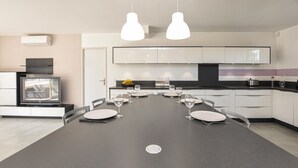 Une cuisine moderne dotée d’un îlot central, de meubles blancs et d’un téléviseur à écran plat.
