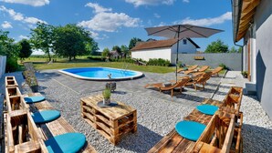 A backyard with a swimming pool, wooden lounge chairs, and a table with a potted plant. - Nice home in Svibovec Podravski with sauna (Svibovec Podravski)