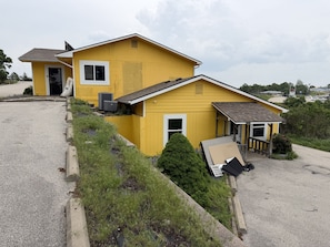Une maison jaune avec un garage, un petit porche et une allée.