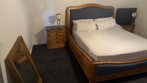 Ein Schlafzimmer mit einem Bett, zwei Nachttischen, einem Spiegel und einem Deckenventilator.