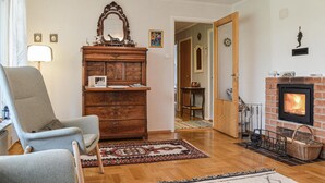 Ein gemütliches Wohnzimmer mit Kamin, einem hölzernen Schmuckkästchen, einem Sessel und einem Teppich.