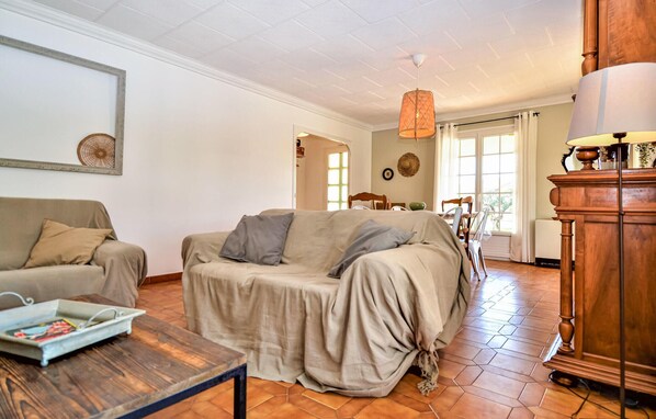 Un salon avec un canapé, une table basse et une lampe. Une porte donne accès à une autre pièce.