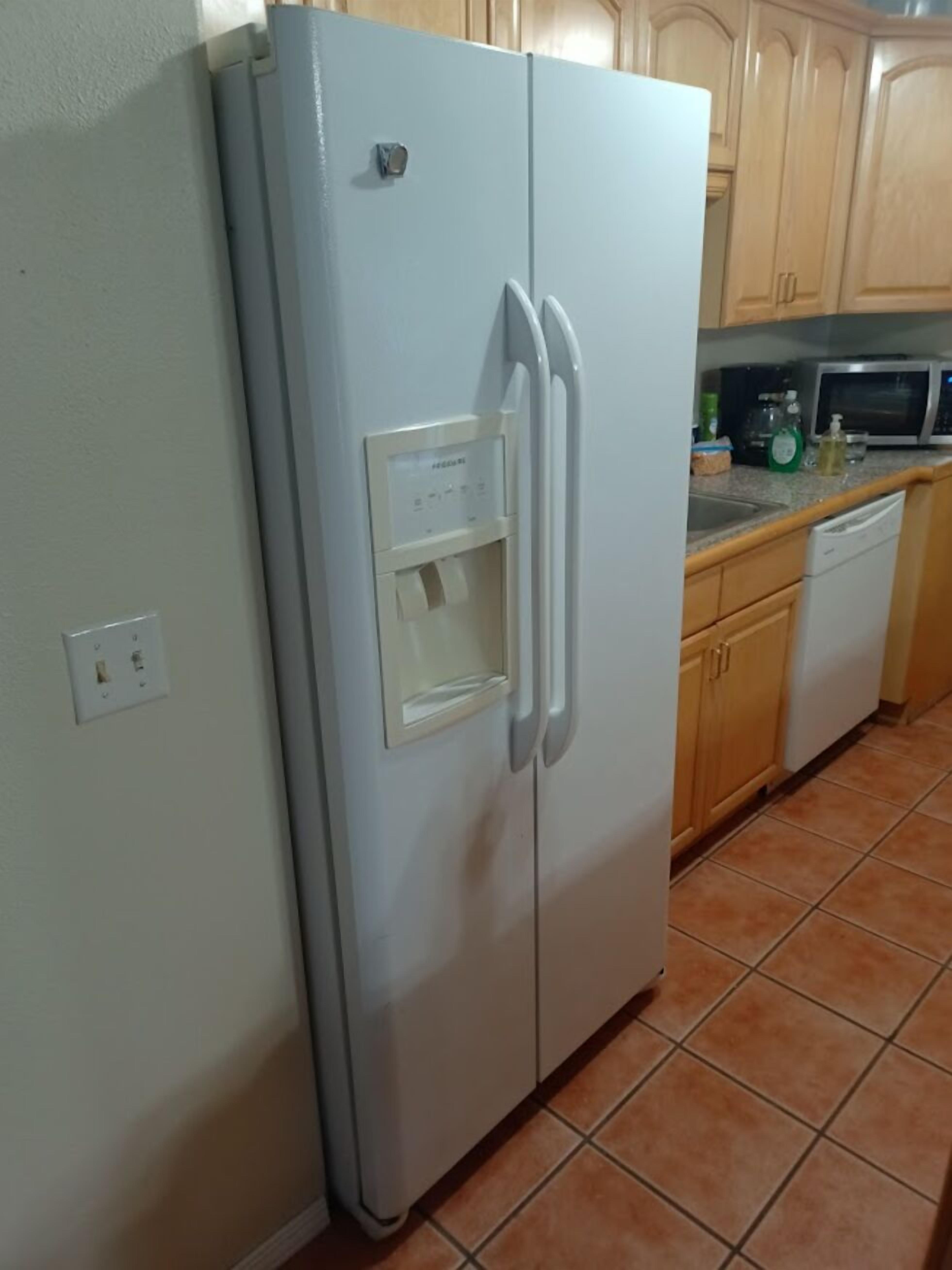 A kitchen with a white refrigerator, a microwave, and wooden cabinets.