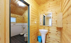 A wooden-paneled bathroom with a sink, toilet, and shower. - Garten In AEWOL (Jeju City)