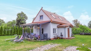 A single-story house with a tiled roof, a covered porch with outdoor furniture, and a paved driveway. - 3 bedroom lovely home in Nowe Warpno (Nowe Warpno)