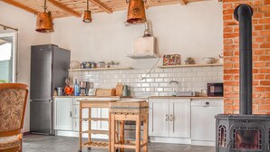 A kitchen with white cabinets, a wooden table, a stove, and hanging copper light fixtures. - 3 bedroom lovely home in Nowe Warpno (Nowe Warpno)