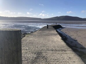 A concrete walkway leading to a beach with a wooden post on the left. - Holly Blue - Cosy Wooden Lodge, Kippford (Dalbeattie)