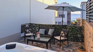 Un balcón con sofá, mesa de centro y un jacuzzi.