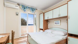 Een slaapkamer met een bed, een bureau en een kledingkast. Er is een raam met uitzicht op het omliggende landschap.