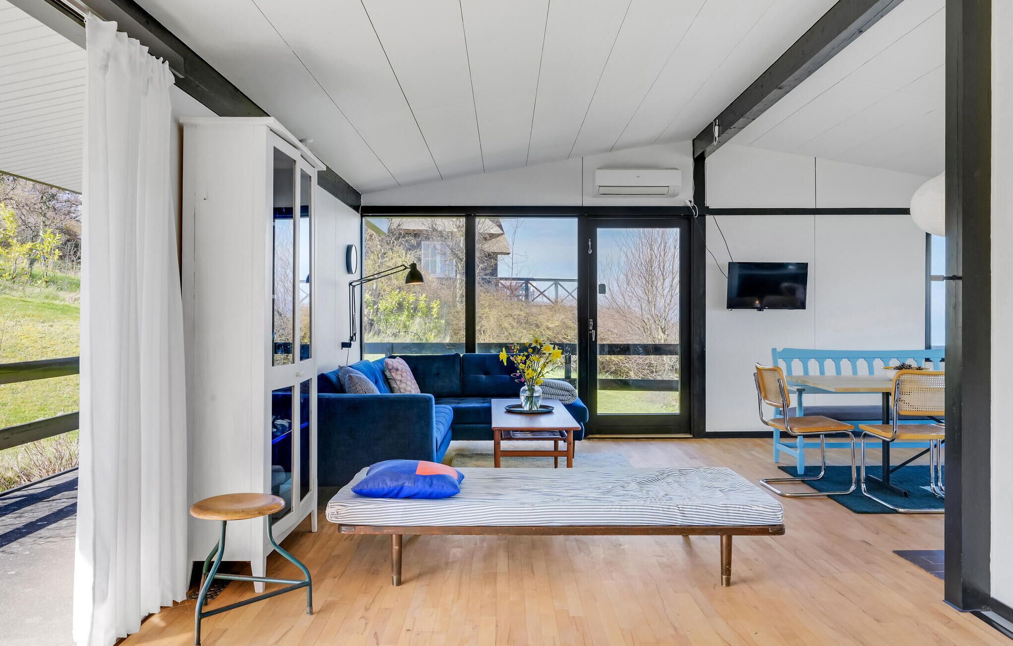 Un vaste espace de vie comprenant un canapé, une table basse et un téléviseur fixé au mur.