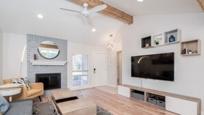 A modern living room with a fireplace, a large TV, and built-in shelves.