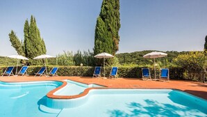 A swimming pool with blue water, surrounded by lounge chairs and umbrellas. - Gorgeous apartment in Montaione (Montaione)