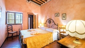 A bedroom with a bed, a chair, a nightstand, a lamp, and a window with blinds. - Gorgeous apartment in Montaione (Montaione)