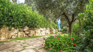 A stone pathway in a garden with green foliage and red flowers. - Gorgeous apartment in Montaione (Montaione)