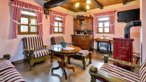Una habitación tradicional con muebles de madera, una mesa redonda y cortinas a cuadros.