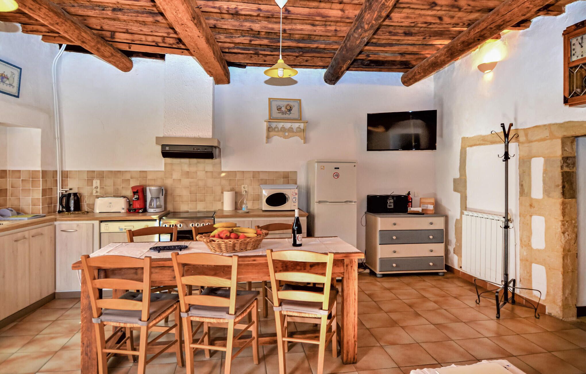 A cozy kitchen with wooden furniture, a tiled backsplash, and a rustic ceiling.