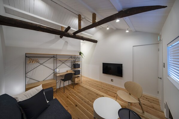 A modern living room with a wooden floor, a sofa, a coffee table, and a TV mounted on the wall. - Japan Sessions KANZAKI 02 (Osaka)