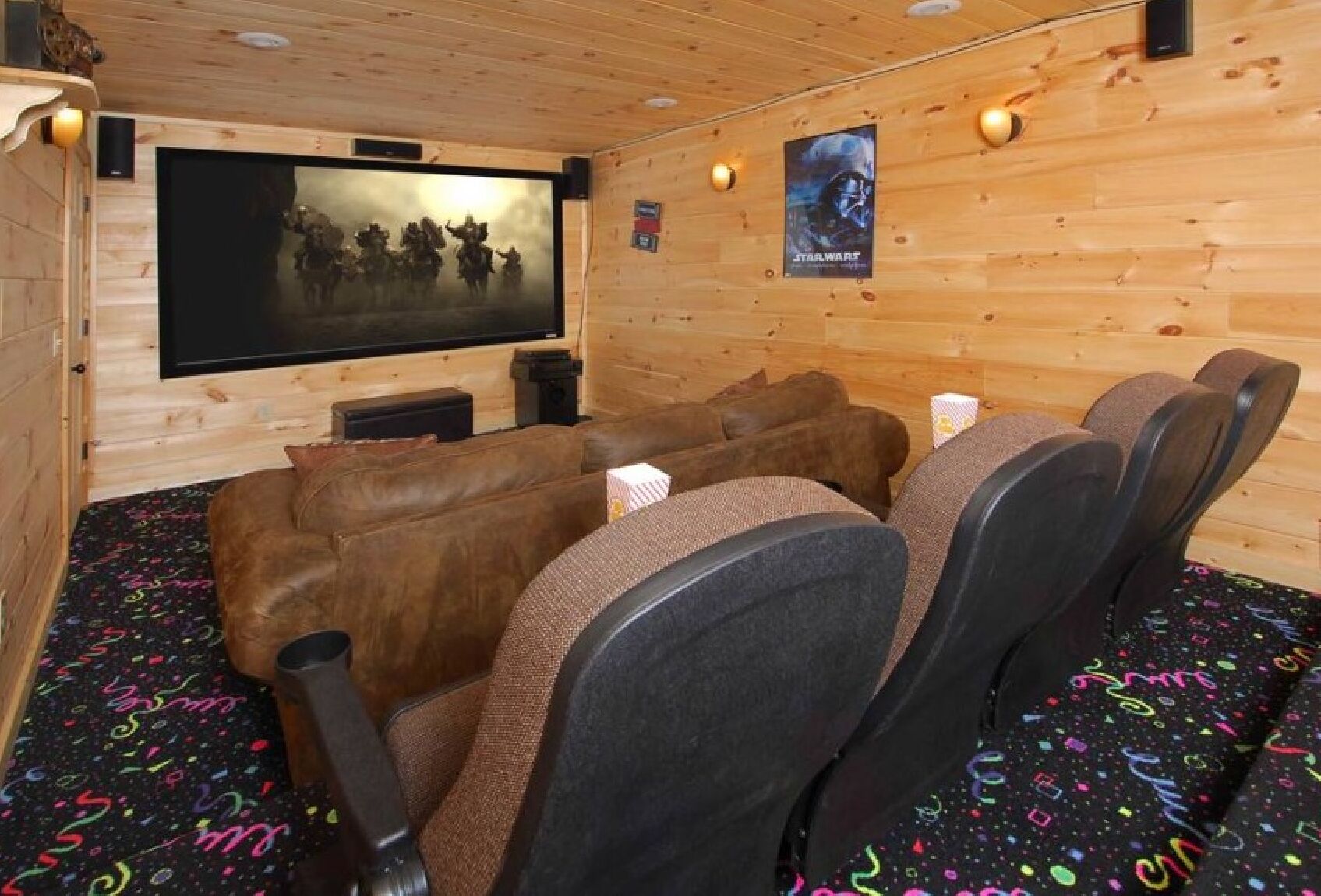 Ein gemütlicher Kinoraum mit Holzwänden, einer großen Leinwand und bequemen Sitzgelegenheiten.