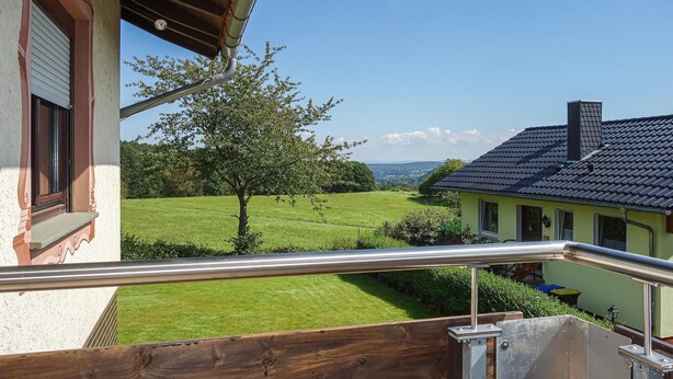 A balcony with a view of a green field, a tree, and a house with a dark roof. - 2 bedroom lovely apartment in Jesberg - Densberg (Jesberg - Densberg)