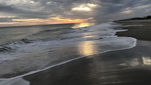 Une plage avec des vagues et un ciel nuageux.