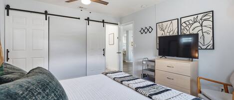 A bedroom with a bed, a TV, a desk, and a chair.