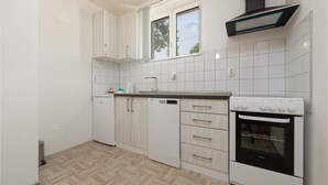A modern kitchen with white cabinetry, a built-in oven, and a window above the sink. - Amazing home in Muskovci (Muskovci)