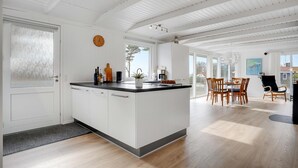 Una cocina moderna con una isla central, armarios blancos y un amplio ventanal que proporciona luz natural.