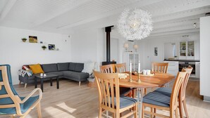 Una sala de estar moderna con comedor, que presenta una gran mesa de madera, sillas, un sofá y una chimenea.