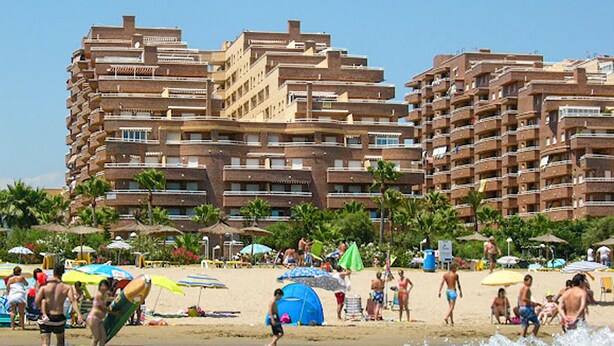 A beach with a row of high-rise buildings in the background.