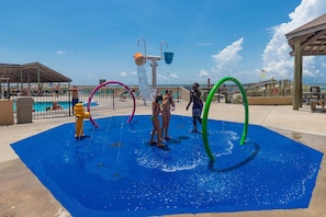 A water play area with multiple water jets and rings, surrounded by a blue mat.