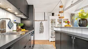 Une cuisine moderne avec des meubles de couleur sombre, des appareils électroménagers en acier inoxydable et un plancher en bois.