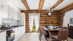 A modern kitchen with white cabinets, a stove, and a dining area with a wooden table and chairs.