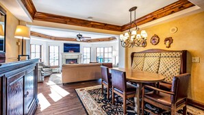 A spacious living area with a fireplace, wooden ceiling beams, and a large window. - Heart of Vail Village - Free Breakfast, Free Parking, No Resort Fee - Walkable (Vail)