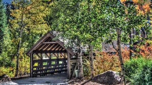 A wooden gazebo with a sloped roof, surrounded by trees and a stone pathway. - Heart of Vail Village - Free Breakfast, Free Parking, No Resort Fee - Walkable (Vail)