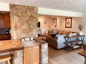 A cozy living area with a stone fireplace, a wooden dining table, and a comfortable sofa. - Large fully-furnished family home nestled in beautiful elk country. (Weedville)