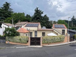 Un edificio residenziale con pannelli solari, un cancello e una scala che conduce a un balcone.