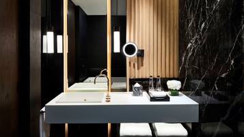 Un baño moderno con un lavabo blanco, un espejo con luz de aro y una pared de paneles de madera.